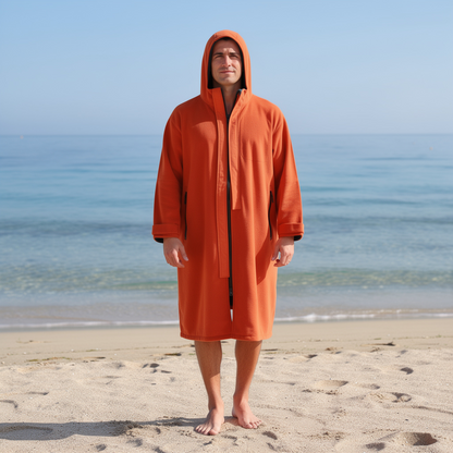 Man wearing an orange hooded surf changing robe on the beach – ShowerNest Australia