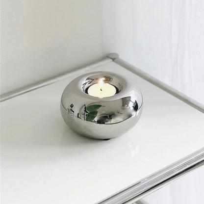 Silver tealight holder glowing in a dark room