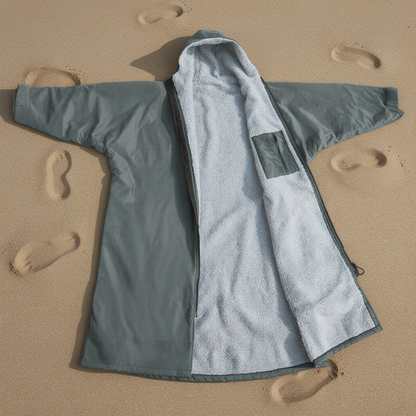 Grey surf changing robe laid open on sand showing the microfibre lining – ShowerNest Australia
