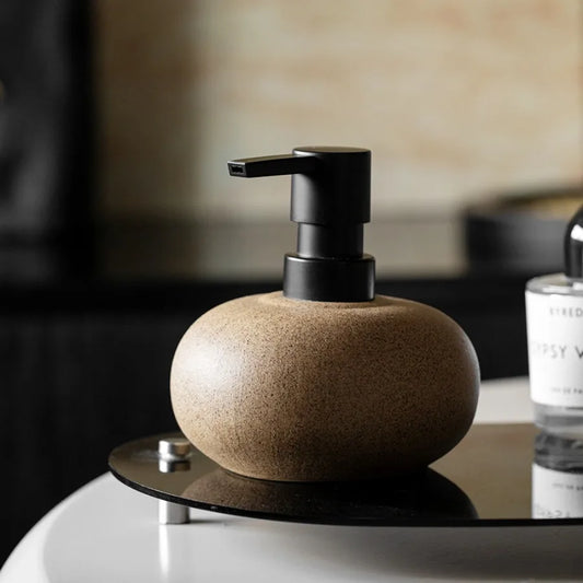 Round sand ceramic soap dispenser on a vanity