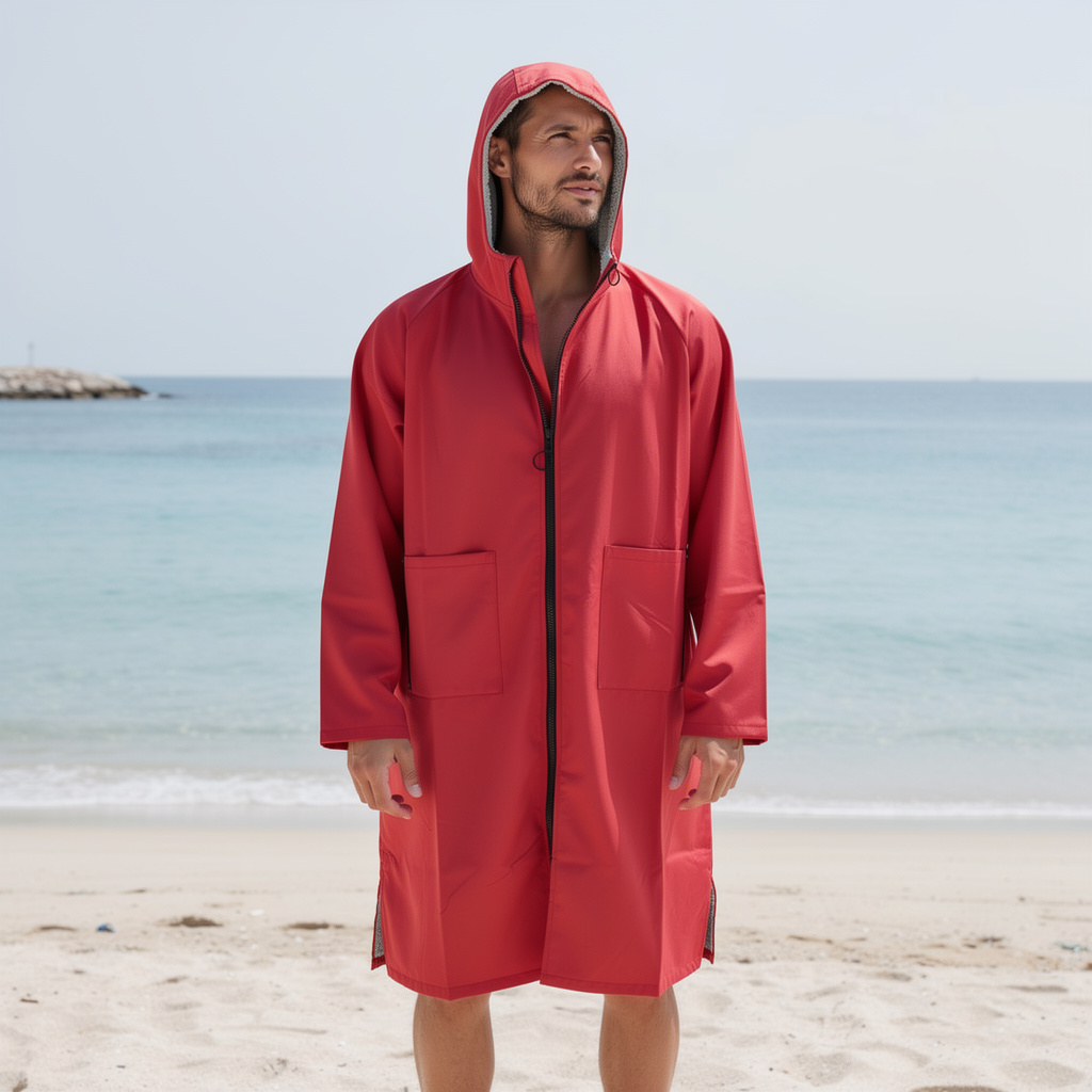 Man wearing a red hooded surf changing robe by the ocean – ShowerNest Australia