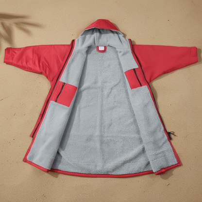 Red surf changing robe laid open on sand showing the grey lining – ShowerNest Australia