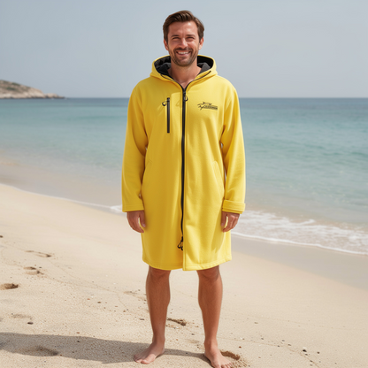 Man wearing a yellow hooded surf changing robe on the beach – ShowerNest Australia