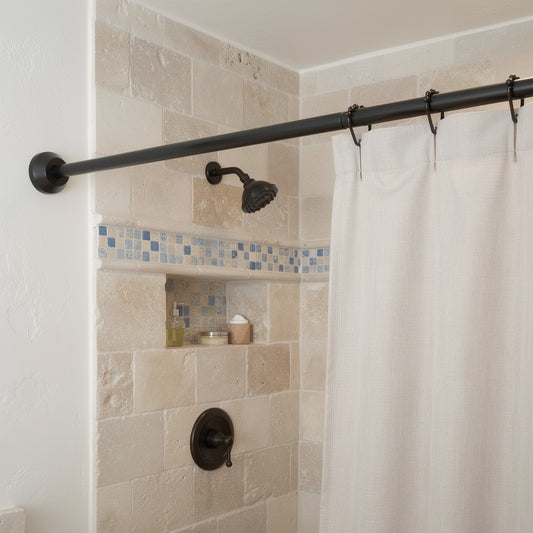 Black shower curtain rod with white curtain in a stone Mediterranean shower