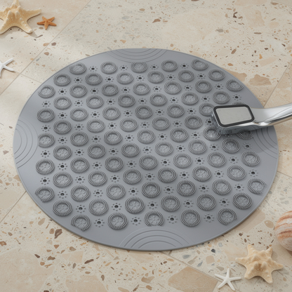grey round suction shower mat with drain holes on a tiled floor – ShowerNest