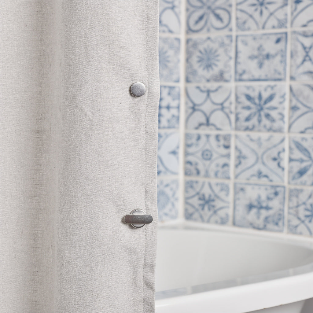 Shower curtain kept closed with a magnetic clip on patterned tiles